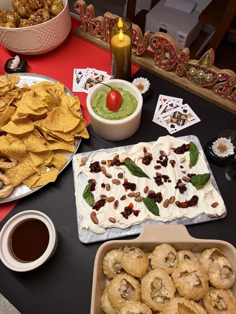 Overhead view of Toronto Canteen catering spread with dips, chips, cookies, candles, and playing cards on a table