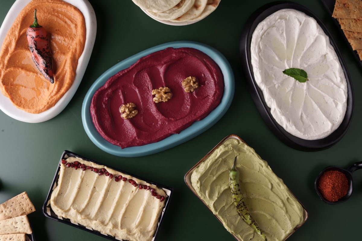 Jars of Toronto Canteen Saucery dips including hummus, beetroot dip, and Bhoot Chili Oil arranged on a wooden surface
