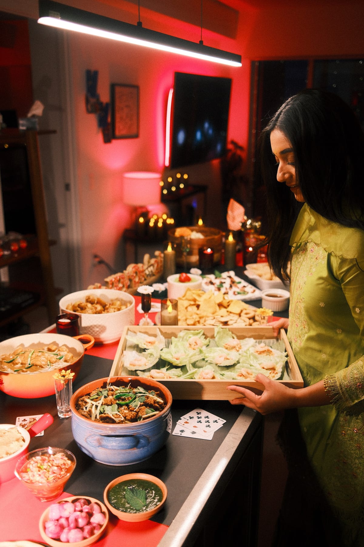Generous spread on a long surface with multiple dishes, bowls of dips, herbs, bread, and candles